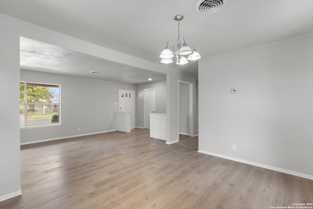 empty room with light hardwood / wood-style flooring and a notable chandelier