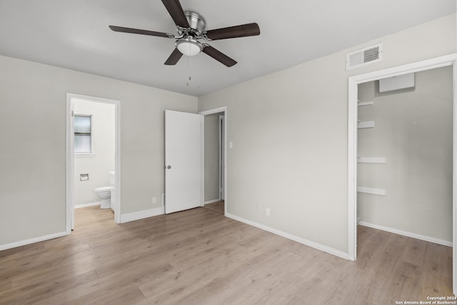 unfurnished bedroom featuring light hardwood / wood-style floors, a closet, ceiling fan, a walk in closet, and ensuite bath