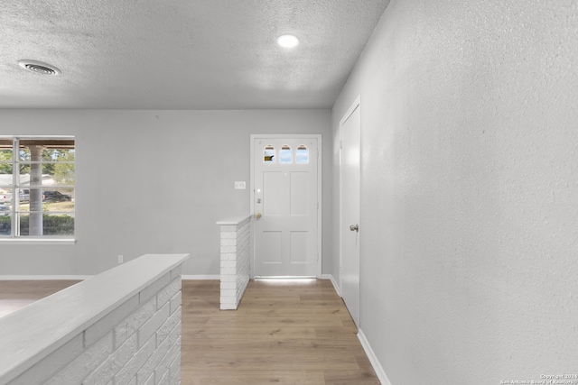 hallway with a textured ceiling and light hardwood / wood-style floors