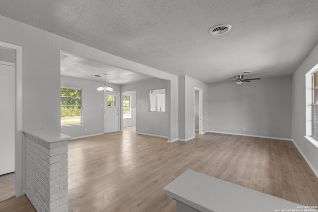 unfurnished living room with light hardwood / wood-style flooring, a textured ceiling, and ceiling fan with notable chandelier