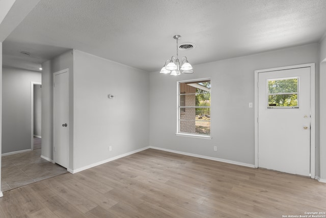 entryway featuring a textured ceiling, light wood-type flooring, and a chandelier