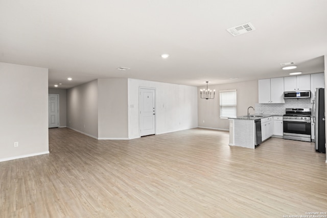 kitchen featuring sink, white cabinetry, stainless steel appliances, an inviting chandelier, and light wood-type flooring