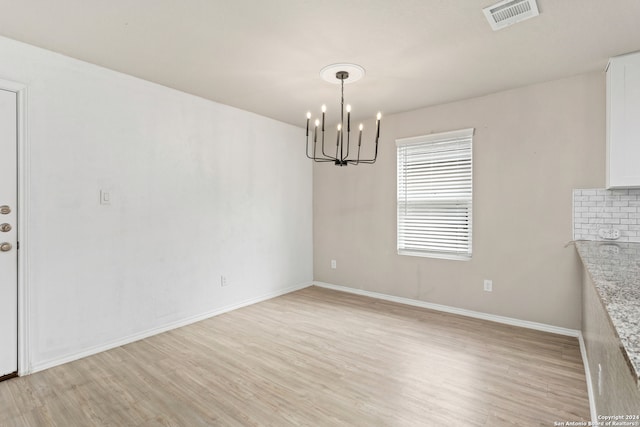 unfurnished dining area featuring an inviting chandelier and light wood-type flooring