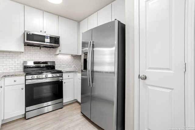 kitchen with light stone counters, white cabinets, stainless steel appliances, and light hardwood / wood-style floors