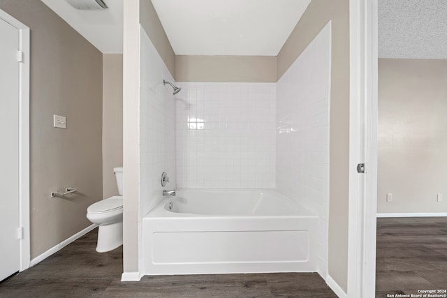 bathroom featuring hardwood / wood-style flooring, tiled shower / bath, and toilet