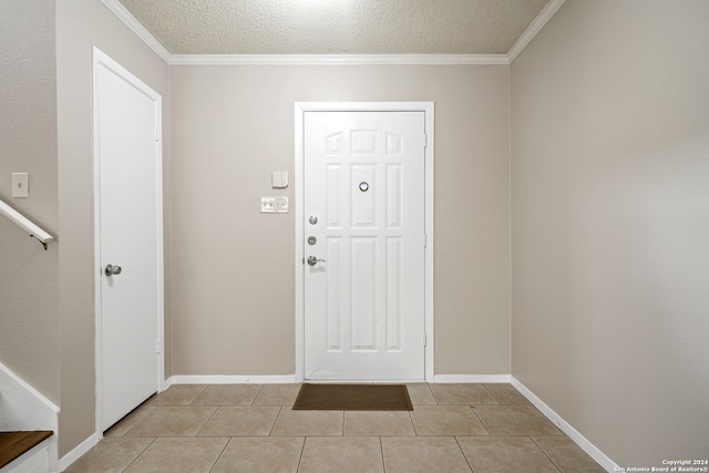 tiled foyer entrance with ornamental molding and a textured ceiling