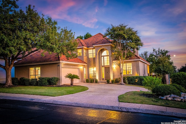 mediterranean / spanish house with a garage and a yard