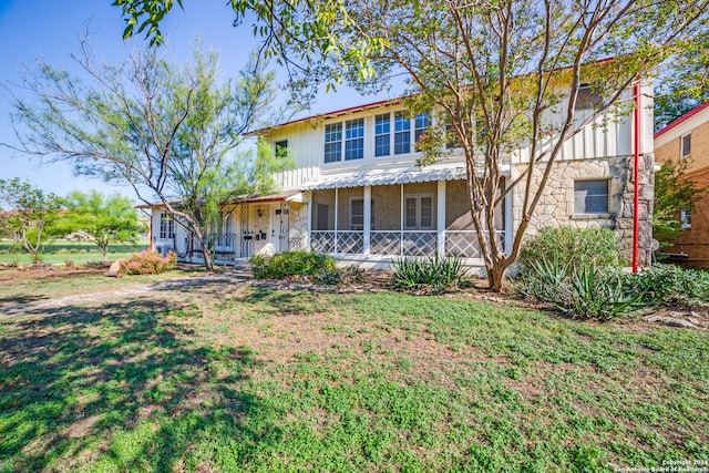 view of front of property featuring a sunroom and a front lawn