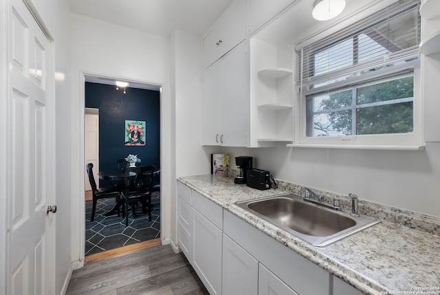 kitchen featuring white cabinets, hardwood / wood-style flooring, light stone countertops, and sink