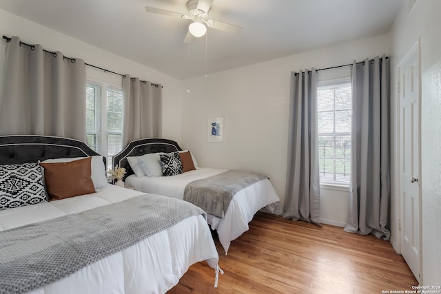 bedroom with ceiling fan, light wood-type flooring, and multiple windows