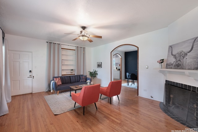 living room with ceiling fan, light wood-type flooring, and built in features