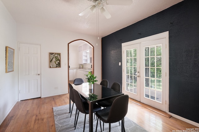 dining area featuring light hardwood / wood-style flooring, ceiling fan, french doors, and a textured ceiling