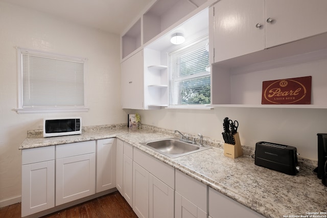 kitchen featuring light stone countertops, dark hardwood / wood-style floors, sink, and white cabinetry