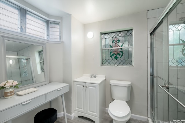 bathroom featuring wood-type flooring, vanity, toilet, and an enclosed shower