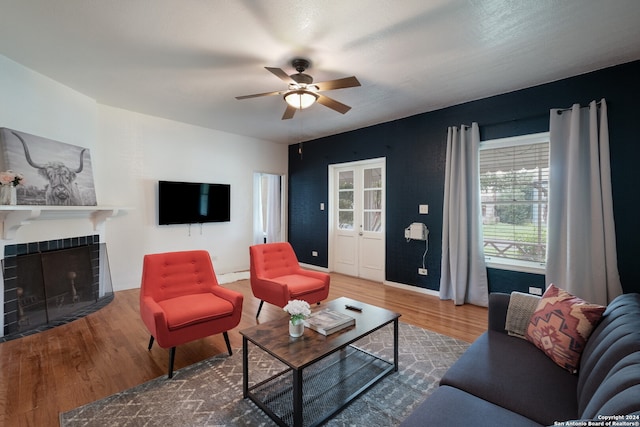 living room featuring a tile fireplace, hardwood / wood-style floors, ceiling fan, and a wealth of natural light