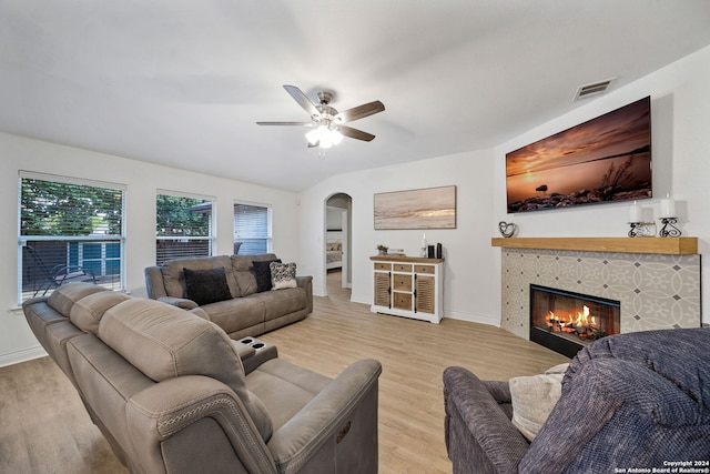 living room with a tile fireplace, ceiling fan, and light hardwood / wood-style flooring