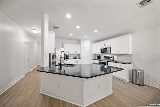 kitchen with white cabinets, kitchen peninsula, stainless steel appliances, light wood-type flooring, and sink