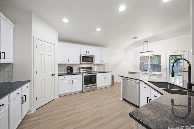 kitchen featuring light wood-type flooring, appliances with stainless steel finishes, decorative light fixtures, and sink