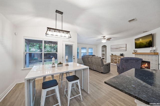 dining area with light wood-type flooring, ceiling fan, plenty of natural light, and a fireplace