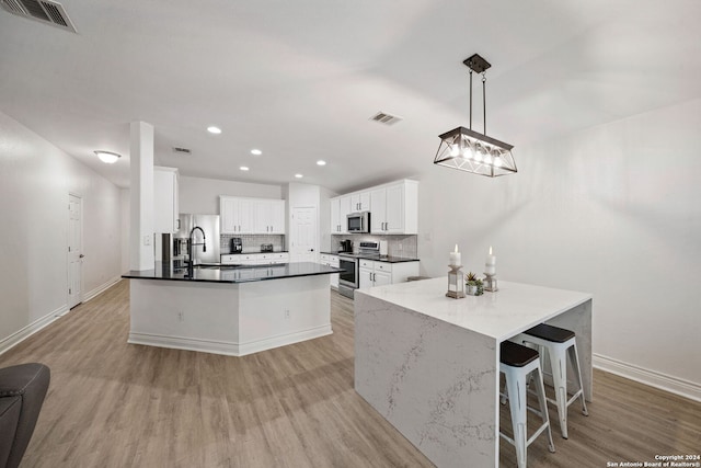 kitchen featuring white cabinetry, pendant lighting, stainless steel appliances, and light hardwood / wood-style flooring