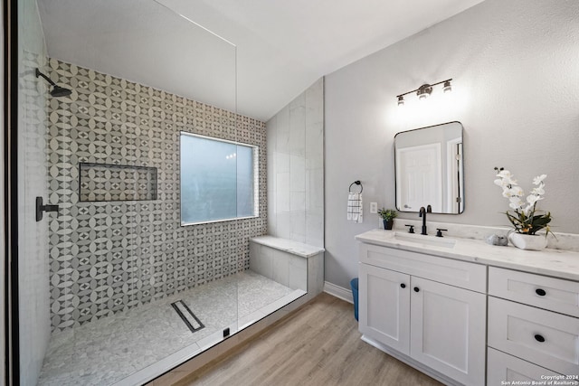 bathroom with a tile shower, lofted ceiling, vanity, and hardwood / wood-style floors