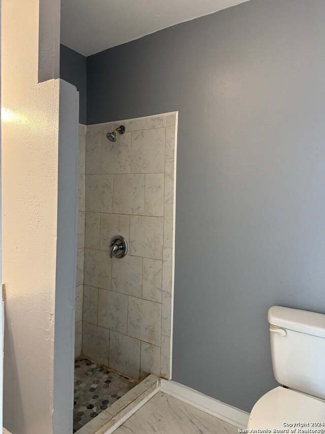 bathroom featuring tiled shower and toilet