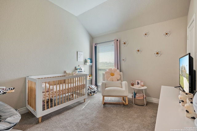 bedroom with lofted ceiling, a crib, and carpet