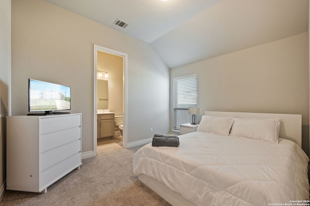 bedroom with light colored carpet, ensuite bathroom, and vaulted ceiling