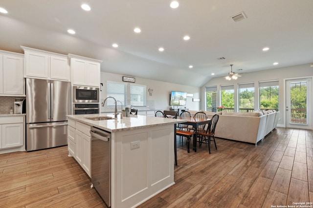 kitchen featuring light wood-type flooring, lofted ceiling, an island with sink, white cabinets, and appliances with stainless steel finishes