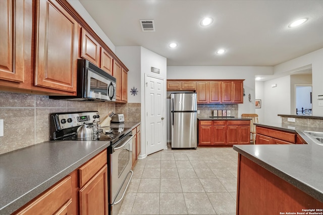 kitchen featuring appliances with stainless steel finishes, decorative backsplash, and light tile patterned floors