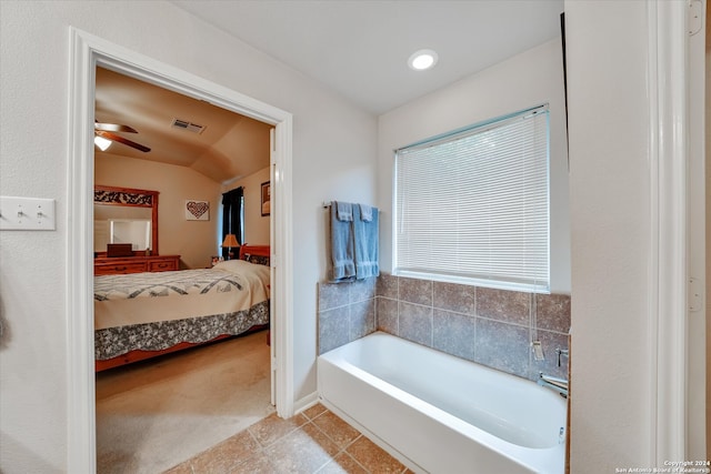 bathroom with vaulted ceiling, a washtub, ceiling fan, and tile patterned floors