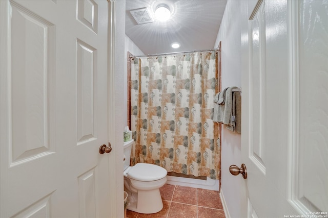 bathroom with tile patterned flooring, walk in shower, and toilet