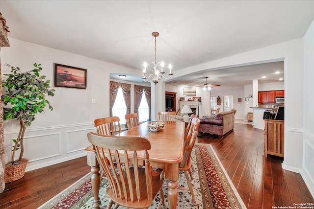 dining room featuring ceiling fan with notable chandelier and dark wood-type flooring