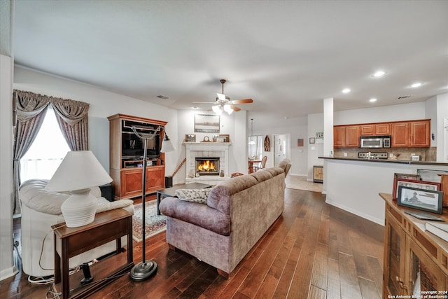 living room featuring ceiling fan, a tile fireplace, and dark hardwood / wood-style floors