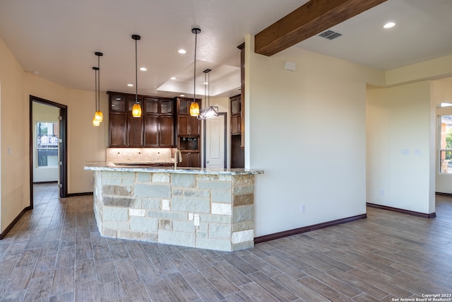 kitchen with dark brown cabinetry, pendant lighting, kitchen peninsula, dark wood-type flooring, and light stone countertops