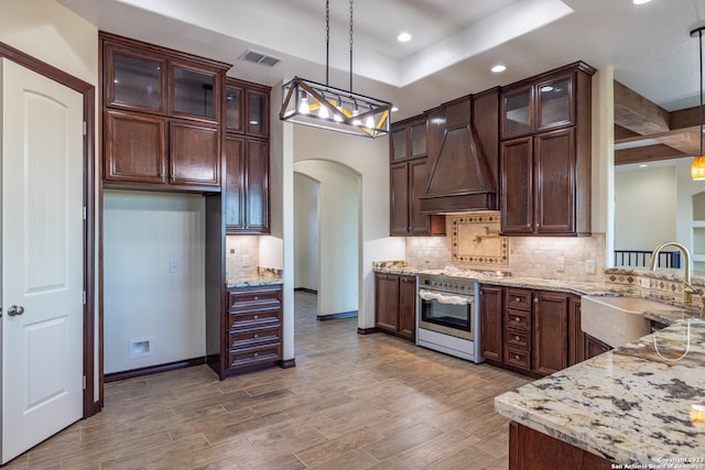 kitchen featuring light stone countertops, wood-type flooring, hanging light fixtures, and sink