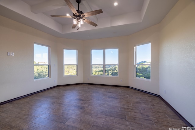 unfurnished room featuring ceiling fan, a tray ceiling, and dark wood-type flooring