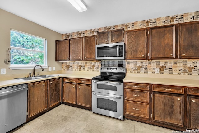 kitchen with dark brown cabinetry, sink, stainless steel appliances, and tasteful backsplash