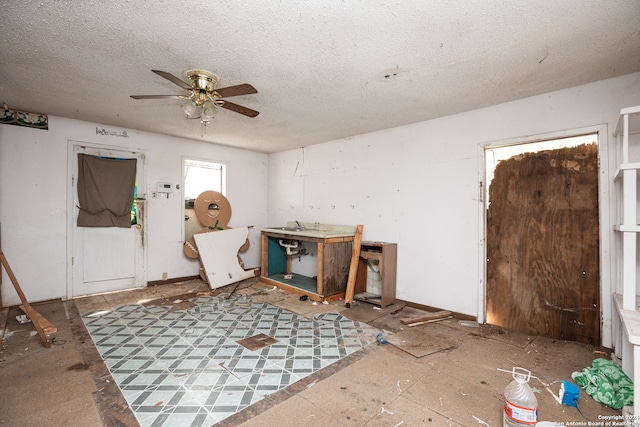 miscellaneous room with ceiling fan and a textured ceiling