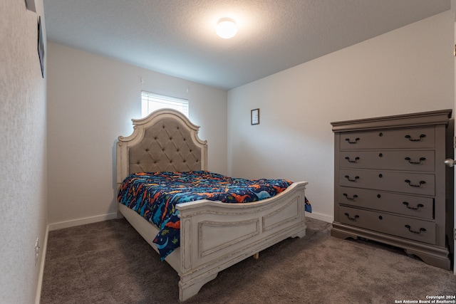 bedroom featuring dark carpet and a textured ceiling