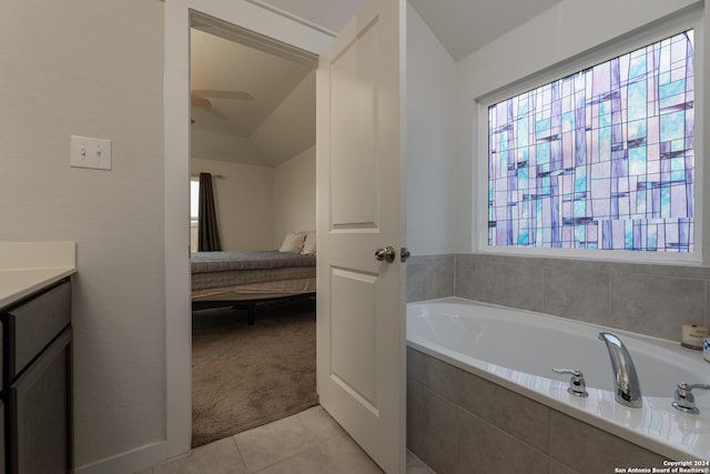 bathroom with tile patterned flooring, lofted ceiling, ceiling fan, tiled bath, and vanity