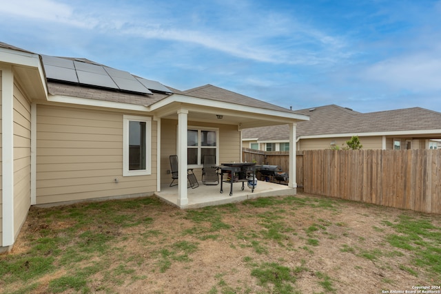 back of house with solar panels, a yard, and a patio area