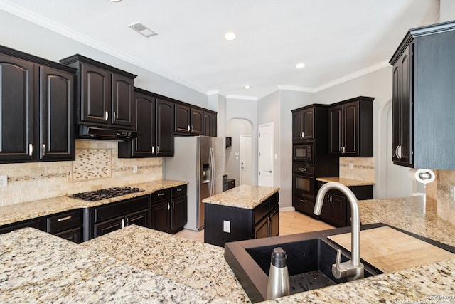 kitchen featuring light stone counters, sink, black appliances, a center island, and crown molding