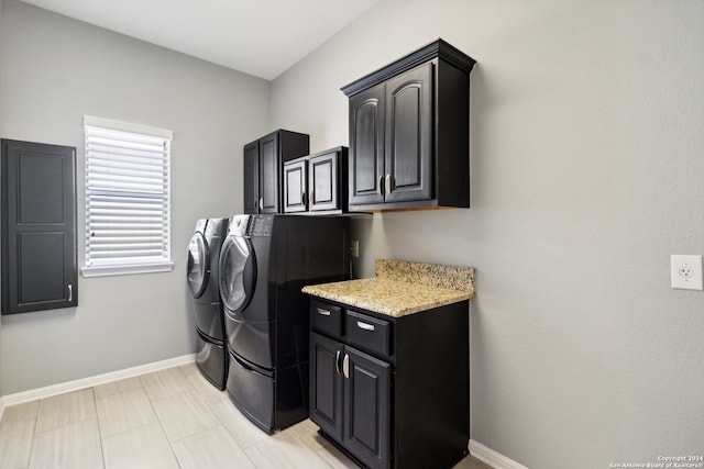 clothes washing area with cabinets, light tile patterned floors, and washer and dryer