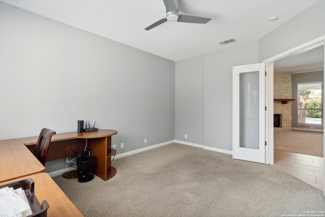 office area featuring a large fireplace, carpet, and ceiling fan