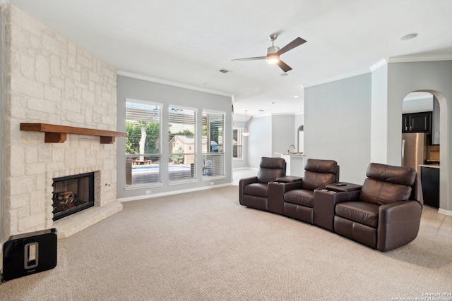 carpeted living room with a fireplace, ornamental molding, and ceiling fan