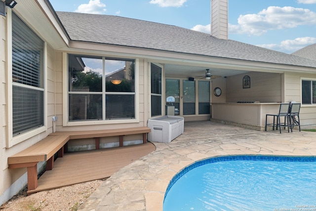 view of swimming pool featuring a wooden deck, an outdoor bar, ceiling fan, and a patio area