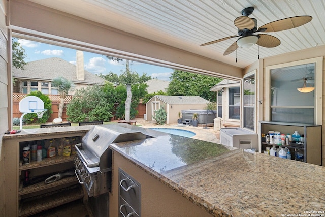 view of patio / terrace featuring a grill, ceiling fan, exterior kitchen, a shed, and a hot tub