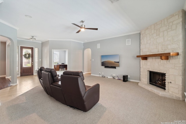 living room featuring ceiling fan, a stone fireplace, crown molding, and light hardwood / wood-style floors