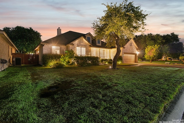 view of front of house with central AC unit, a garage, and a lawn